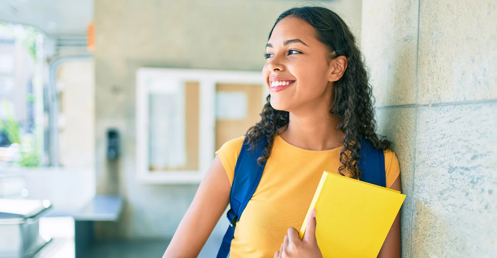 a woman with a backpack holding a book campus learning