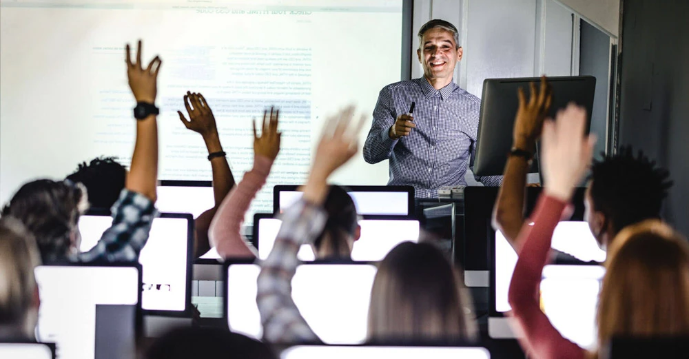 An instructor in a computer lab taking questions from students.