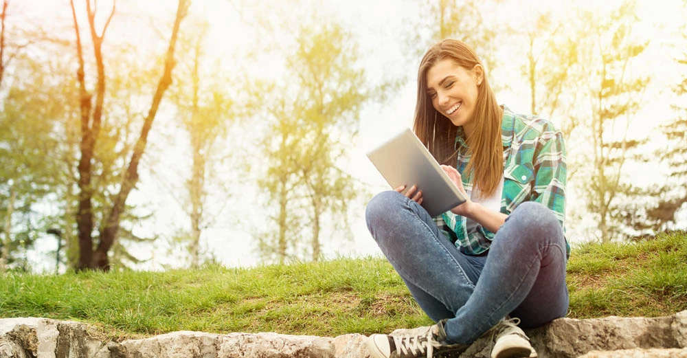 a woman sitting on a rock looking at a tablet gratitude in your life and career