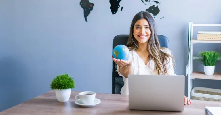A woman sitting at a desk holding a globe.
