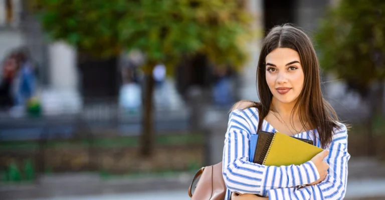 woman outside at college holding a book