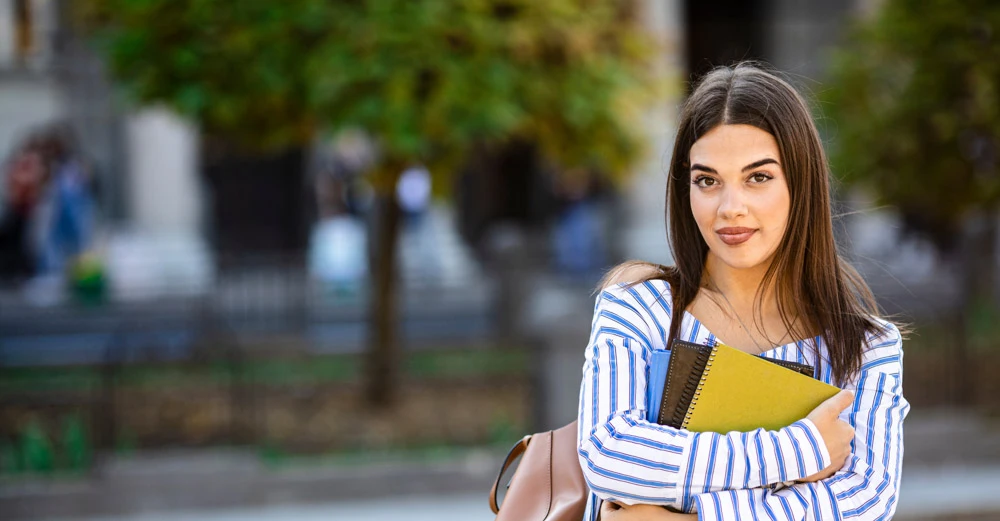woman outside at college holding a book