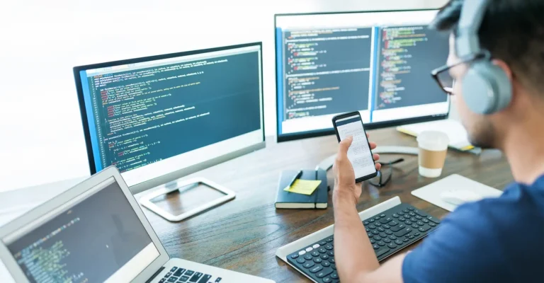 A mobile app developer coding on a computer.