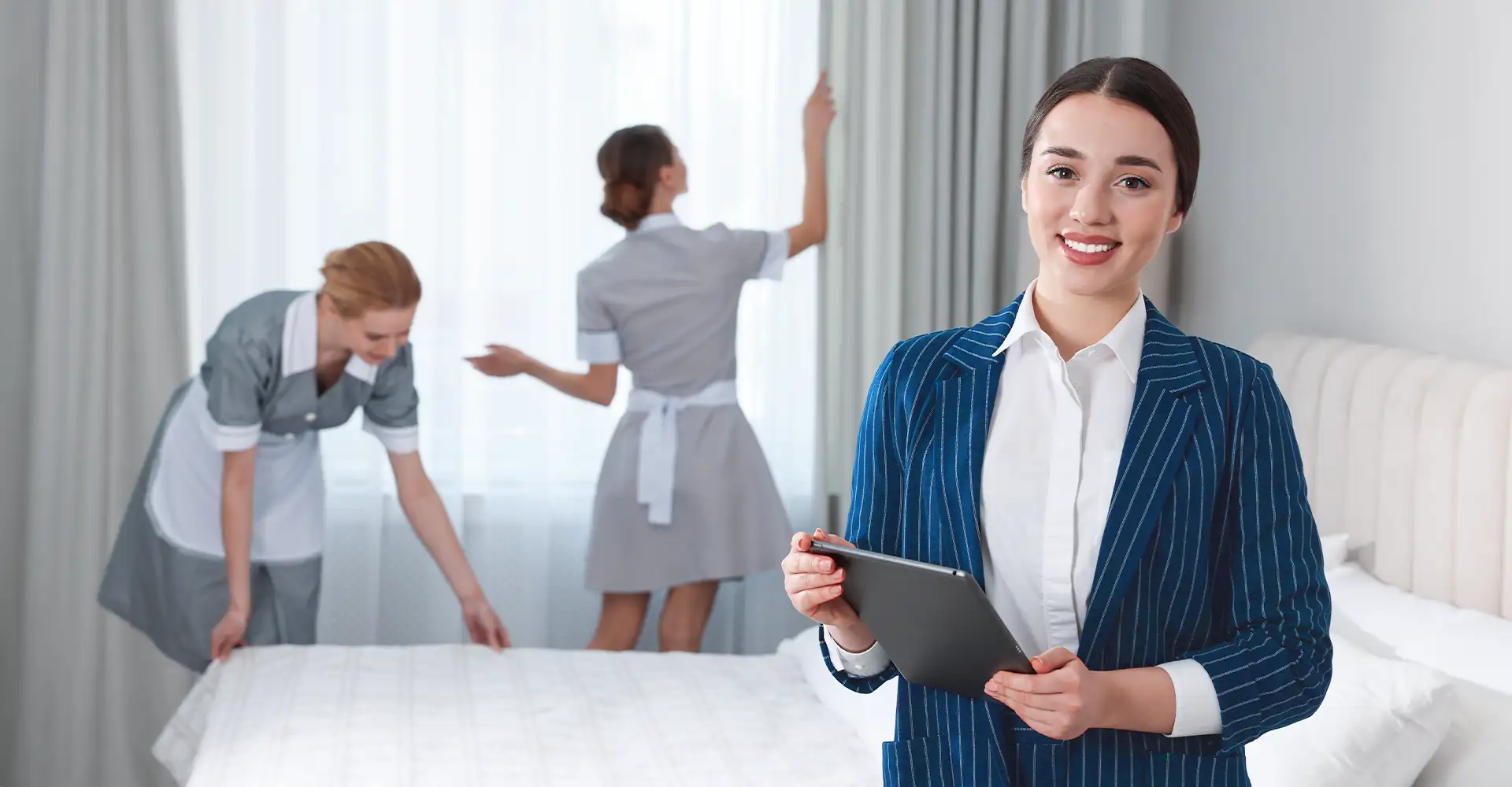 A hospitality manager in a hotel room with two housekeepers.