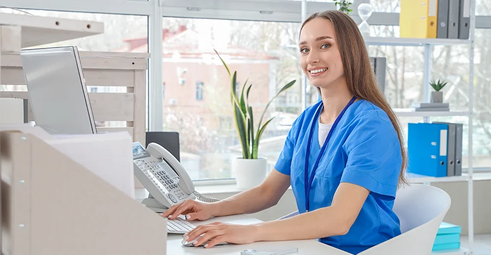 Medical Office Administrator sitting at a desk and working at a computer.