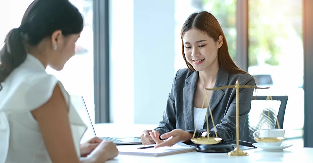 Legal assistant working on a case file with a client, highlighting the importance of good communication skills in law careers.
