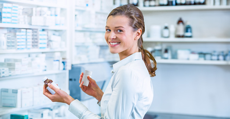 Woman holding medication and glasses in pharmacy, representing career start with pharmacy training.