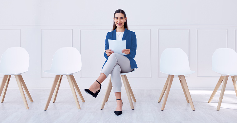 Smiling woman in blazer at desk with scales and gavel, prepared for a legal admin interview.