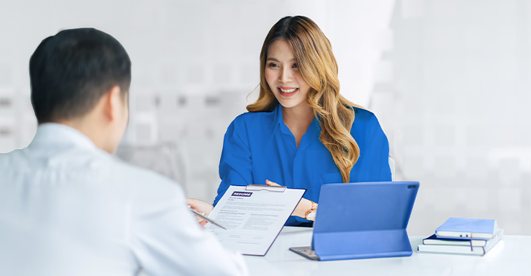 A young graduate sits across from a hiring manager during an interview for a medical office assistant position.