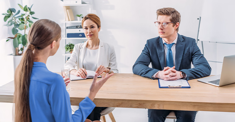 A woman being interviewed for an accounting position by a panel of two hiring managers.