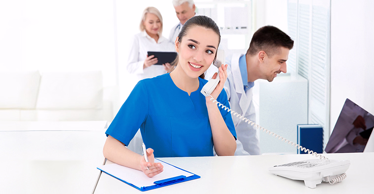 A medical office assistant takes notes while working at a doctor’s office.