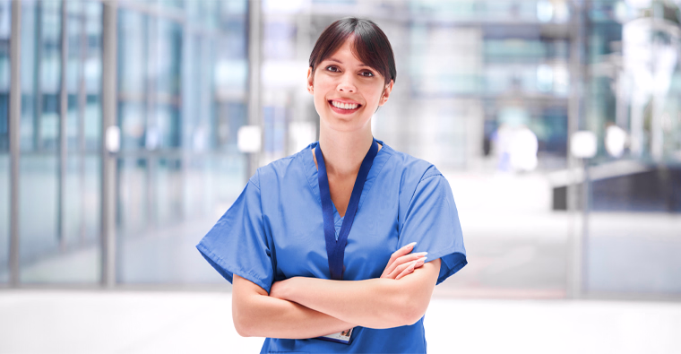 A medical office assistant stands behind a desk, holding files.